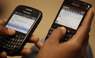 Une femme tient dans les mains deux Blackberry.