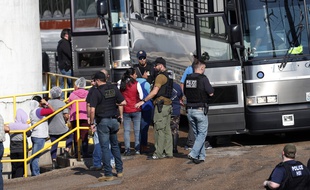 Des travailleuses menottées sont escortées vers un bus qui les emmènera dans des centres de détention. Usine Koch Foods, Morton, le 7 août 2019