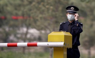 Un agent de sécurité porte un masque devant l'hôtel Guo Men à Pékin, le 5 mai 2009.