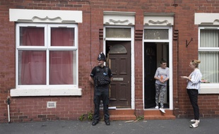 Un officier de police se tient devant un appartement perquisitionné sur Lindum Street à Moss Side, à Manchester, le 25 mai 2017, après l'attaque d'un kamikaze pendant un concert pop lundi soir.