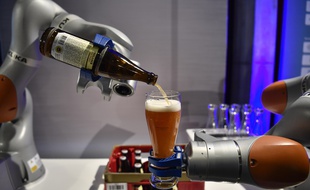 Deux bras robotiques du fabricant de robots industriels Kuka versent une bière pour les invités participant au Sommet du Business20 (B20) à Berlin le 2 mai 2017.