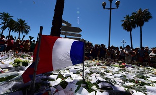 Un drapeau français entouré de bouquets de fleurs et autres hommages aux victimes de la tuerie de Nice perpétrée jeudi 14 juillet sur la promenade des Anglais.
