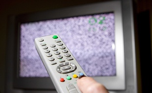 Un télécommande devant un écran de télévision qui grésille.