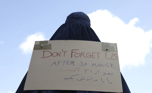 Une femme afghane tient un panneau où est écrit: « Ne nous oubliez pas après le 31 août ».