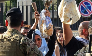 Une manifestante libanaise munie d'une casseroles devant une succursale de la banque centrale lors des manifestations antigouvernementales en cours à Sidon (Saïda), une ville du sud du Liban, le 8 novembre 2019.