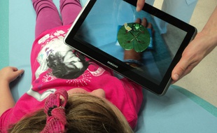 Grâce à la réalité augmentée, le personnage virtuel dédramatise l'acte médical et rassure l'enfant.