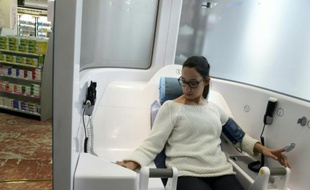 Guidée par un ordinateur, une femme prend sa tension dans une cabine de télémédecine, à Roanne, le 11 mars 2016