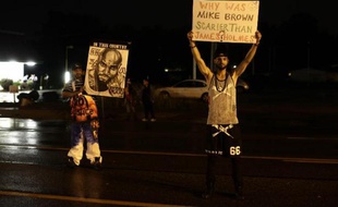 Des manifestants protestent dans les rues de Ferguson, le 16 août 2014 contre la mort du jeune noir Michael Brown tué par un policier quelques jours plus tôt