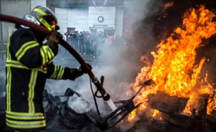 Un pompier éteint un début d'incendie devant la prison de Villefranche-sur-Saône après une manifestation de gardiens de prison le 6 mai 2014 contre la surpopulation carcérale et le manque de moyens sanitaire pour les détenus