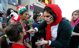Une supportrice iranienne maquille une jeune fille avant le match contre le Maroc à Kazan.