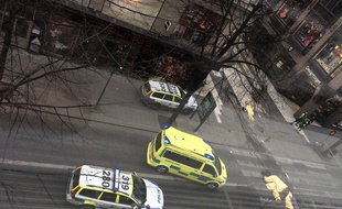 An ambulance standsa near covered bodies at the scene where a truck crashed into the Ahlens department store at Drottninggatan in central Stockholm, April 7, 2017.