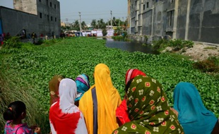 Des femmes bangladaises regardent le 24 avril 2016 le site où s'est effondré le bâtiment du Rana Plaza il y a trois ans, dans lequel plus de 1.100 personnes avaient trouvé la mort, près de Dhaka