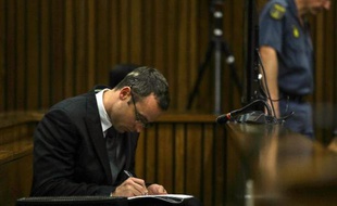 Oscar Pistorius prend des notes lors de son procès, à Pretoria le 11 mars 2014