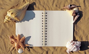 illustration d'un cahier de vacances sur le sable.
