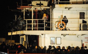 Des refugiés syriens attendent de débarquer au port italien de Gallipoli, le 31 décembre 2014. Leur bateau, le Blue Sky M, a été secouru par les gardes-côtes italiens, après avoir été abandonné avec quelque 800 personnes à bord par les passeurs