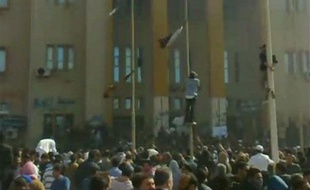 Des manifestants grimpent sur des poteaux devant un bâtiment de la sécurité intérieure à Benghazi, en Libye, le 20 février 2011.