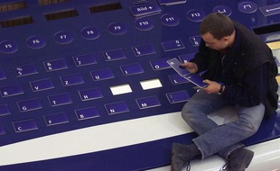 Un homme réassemble les lettres d'un clavier géant, à Hanovre (Allemagne), en février 2000.
