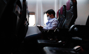 Un homme portant un masque de protection contre le Covid-19 à bord d'un avion. (illustration)