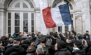 Un groupe agite le drapeau français en soutien au général Christian Piquemal, accusé d'avoir participé à une manifestation interdite contre les migrants, devant le tribunal de Boulogne-sur-Mer, le 8 février 2016