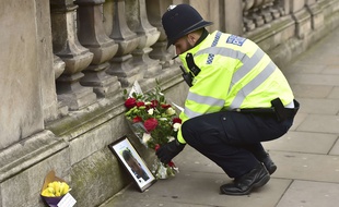 A police officer places flowers and a photo of fellow police officer Keith Palmer, who was killed in yesterdays attack, on Whitehall near the Houses of Parliament in London, Thursday March 23, 2017. On Wednesday a knife-wielding man went on a deadly rampage, first driving a car into pedestrians then stabbing a police officer to death before being fatally shot by police within Parliament's grounds in London.