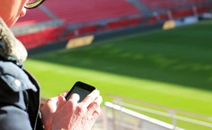 Illustration d'un homme utilisant son smartphone au Roazhon Park, l'antre du Stade Rennais.