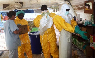 Des membres de Médecins Sans Frontières s'équipent de vêtements de protection pour entrer dans une zone d'isolement pour malades ayant contracté le virus Ebola, le 29 juin 2014 à Conakry