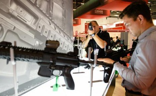 Des visiteurs inspectent des armes Sig Sauer, pistolets et fusils semi-automatiques, durant un salon de l'équipement de défense et de sécurité à Londres le 15 septembre 2015