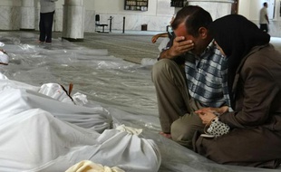 Photo fournie par le réseau d'opposition syrienne Shaam News montrant un couple pleurant face aux cadavres de proches, tués lors d'une attaque qui pourrait être d'origine chimique, le 21 août 2013 près de Damas