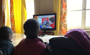 De jeunes enfants d'origine africaine devant les dessins animés à la télévision à Thal-Marmoutier où ces familles de réfugiés préparent leur installation en France. Illustration