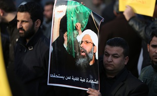 Un homme tient une pancarte représentant l'émir exécuté lors d'une manifestation à Bagdad en Irak.