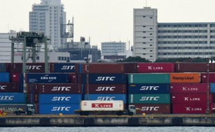 Un camion passe à côté d'une pile de conteneurs dans un port de Tokyo le 8 décembre 2015