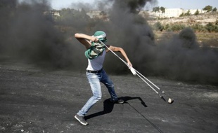 Un Palestinien utilise un lance-pierre pour lancer des projectiles sur les forces de sécurité israéliennes à Beit El, près de Ramallah en Cisjordanie, le 11 octobre 2015