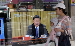 Une femme et son bébé devant une télévision diffusant l'allocution de Xi Jinping, à New Taipei City, le 2 janvier 2018.