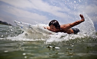 Un jeune garçon s'amuse avec une planche de surf faite en bouteille de plastique.