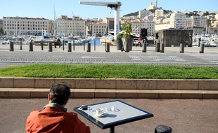 Un homme attablé à une terrasse sur le Vieux-Port, côté mairie