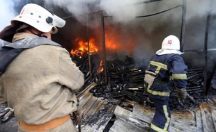 Des pompiers éteignent le 3 juin 2015 un incendie dans un marché de Donetsk, dans l'est de l'Ukraine, provoqué par les combats entre l'armée et les forces séparatistes prorusses