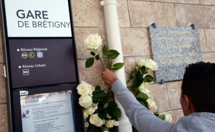 Un homme dépose une fleur à la gare de Brétigny-sur-Orge, le 12 juillet 2014, un an après la catastrophe qui a causé la mort de 7 personnes