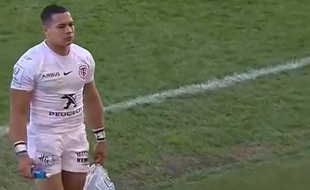 Cheslin Kolbe, l'ailier du Stade Toulousain, en train de ramasser les déchets en bord de terrain.