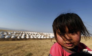 Une petite fille irakienne et, au loin derrière elle, les tentes du camp de déplacés de la ville de Tal Afar, tombée aux mains des insurgés, le 24 juin 2014