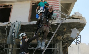 Des bénévoles du service de défense civil syrien évacuent des gens d'un immeuble détruit par des bombardements, dans un quartier rebelle d'Alep le 23 avril 2016