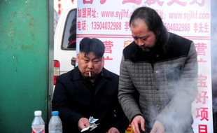 Un vendeur de brochettes (g) dont la ressemblance avec le dirigeant nord-coréen Kim Jong-Un est étonnante, attend le chaland le 22 mars 2014 derrière son barbecue dans la ville de Shenyang, au nord-est de la Chine