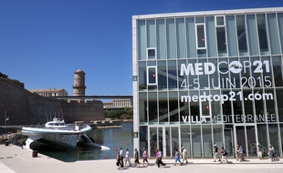 PlanetSolar, the largest solar catamaran (L), moors by the Villa Mediterranee building in Marseille, southern France, on June 3, 2015, on the eve of the opening of the two-day MEDCOP21 climate summit. AFP PHOTO / BORIS HORVAT