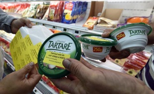 Des agriculteurs collent des autocollants disant "fabriqué avec du lait vendu à perte" sur des produits laitiers dans un supermarché à Luc-la-Primaube près de Rodez le 18 août 2015