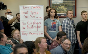 Bob Welch, debout à gauche, et Jim Dillon, brandissent une pancarte lors d'une réunion publique au sujet de l'exercice militaire Jade Helm 15 à Bastrop, au Texas.