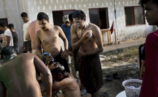 Des migrants afghans font leur toilette dans un hôtel abandonné où ils ont trouvé refuge sur l'île grec de Kos, le 10 août 2015