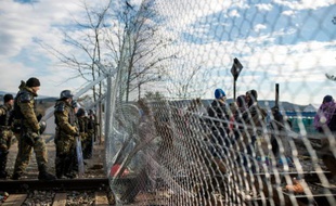 Des policiers macédoniens montent la garde devant des migrants près de la frontière grecque près de Gevgelija en Macédoine le 29 novembre 2015