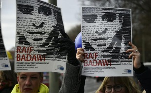 Des membres de l'ONG Amnesty International brandissent des portraits du blogueur saoudien Raef Badawi lors d'une manifestation devant l'ambassade d'Arabie saoudite à Berlin, le 8 janvier 2016.