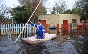 Un enfant navigue sur un matelas dans une rue inondée d'Asucion au Paraguay le 2 juillet 2014