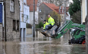 Des employés communaux patrouillent dans la benne d'un tracto-pelle dans les rues inondée de Saint-Étienne-au-Mont, le 27 novembre 2009.