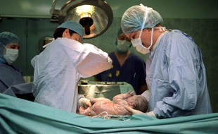 Des gynécologues-obstétriciennes posent un nouveau-né sur le ventre de la mère, le 27 juillet 2001.